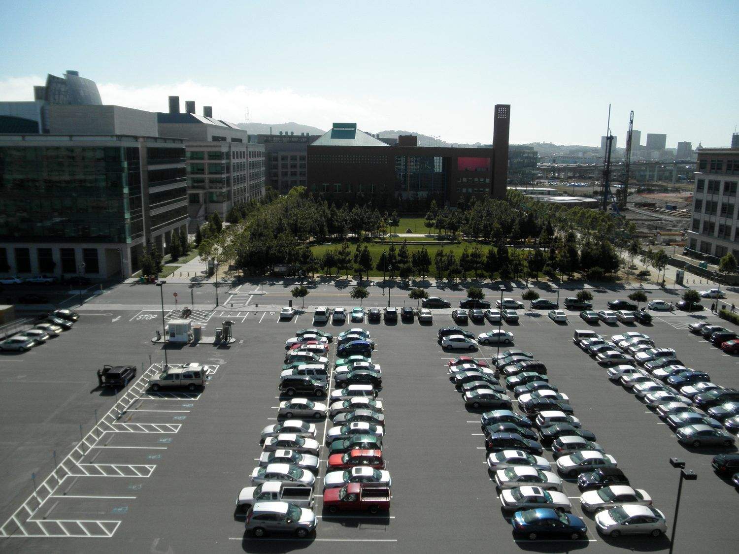 High-angle view of a large institutional campus parking lot filled with cars, showcasing well-maintained pavement marking and line striping.